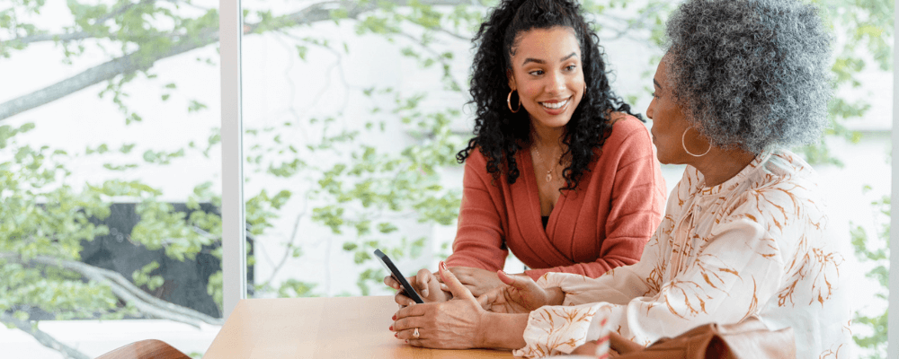 How to Run iMessage on Android - Two people using a smartphone sitting at a table