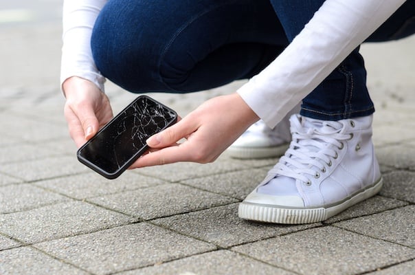 Woman's hands holding broken phone after dropping it on the ground