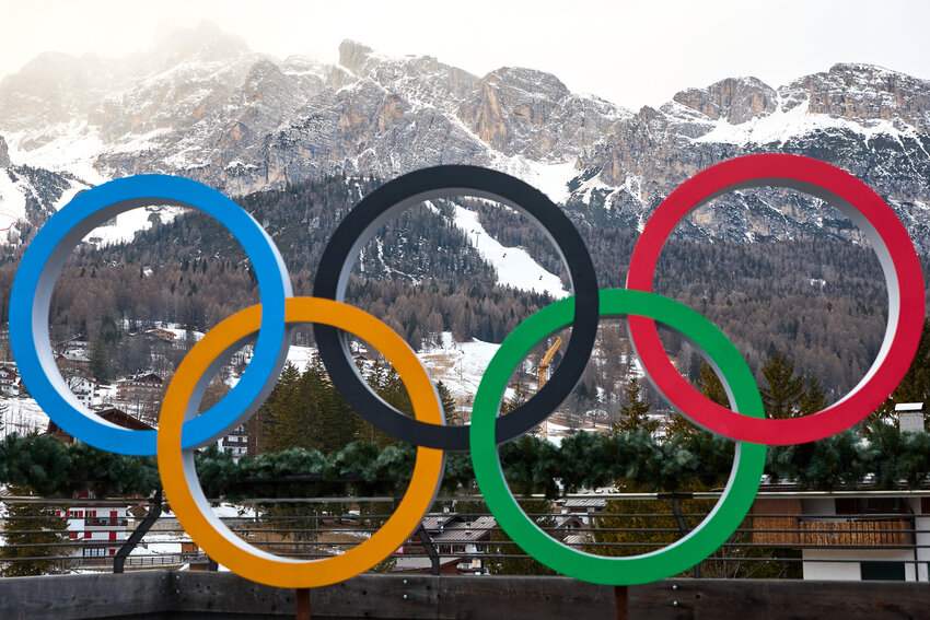 Olympic rings in front of snowy mountain range.