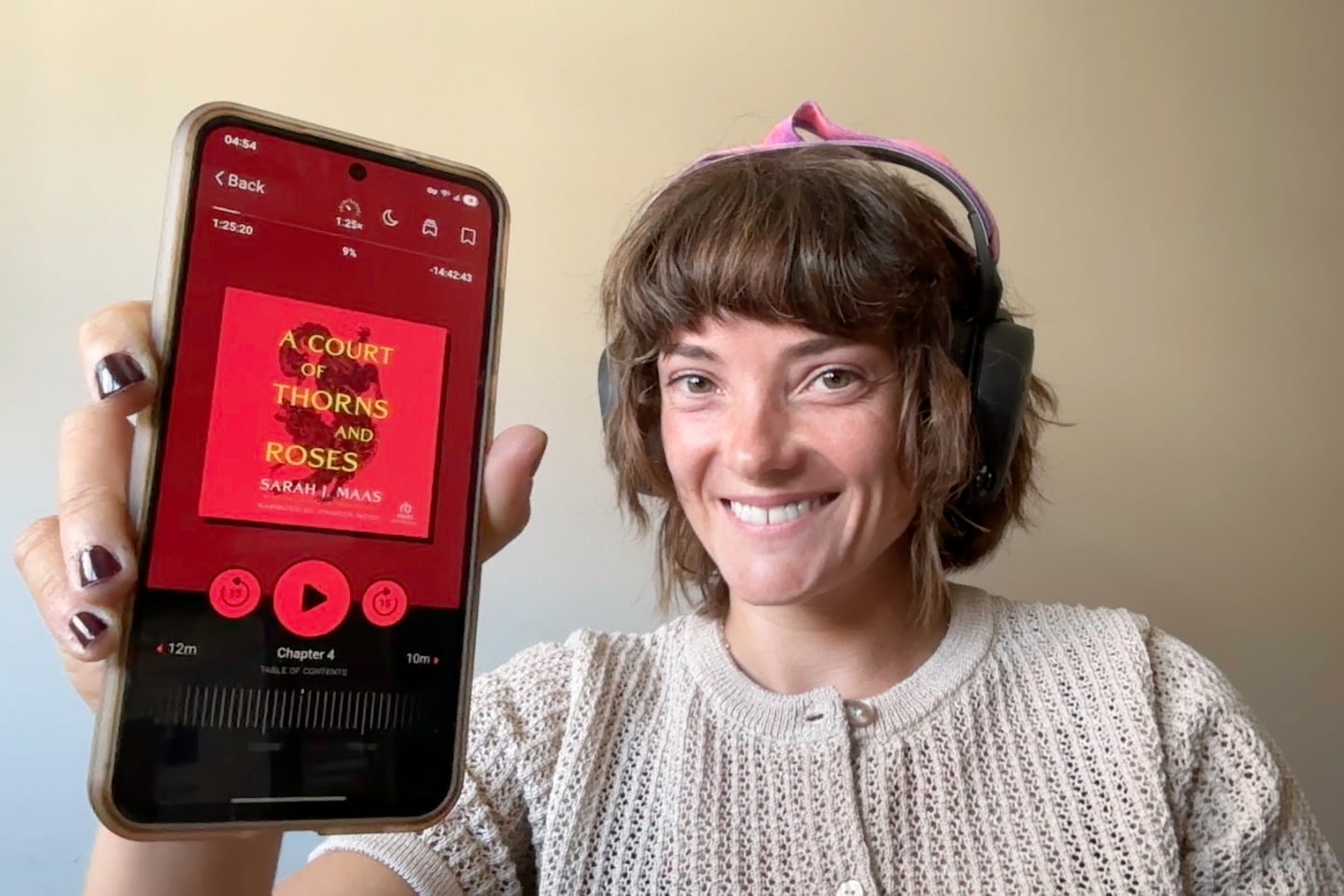 Jessica holing up a Samsung phone with Libby on the screen An image of Jessica holding up her phone with libby showing on the screen reading A Court of Thorns and Roses.