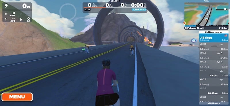 Zwift in-game screenshot showing volcanic terrain in Watopia with other riders