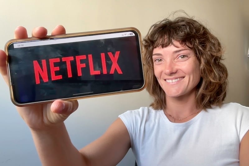 Jessica holding up her phone with the Netflix logo