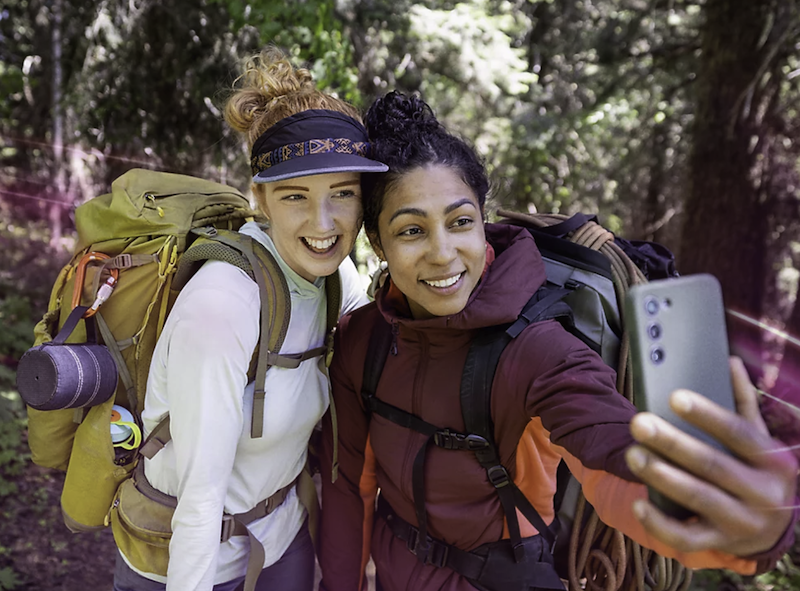 Two women on a backpacking trip taking a selfie. TITLE: Two women on a backpacking trip taking a selfie.