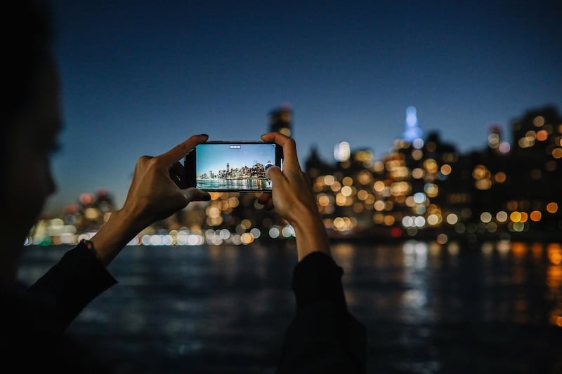 Person taking a picture of a skyline on a phone