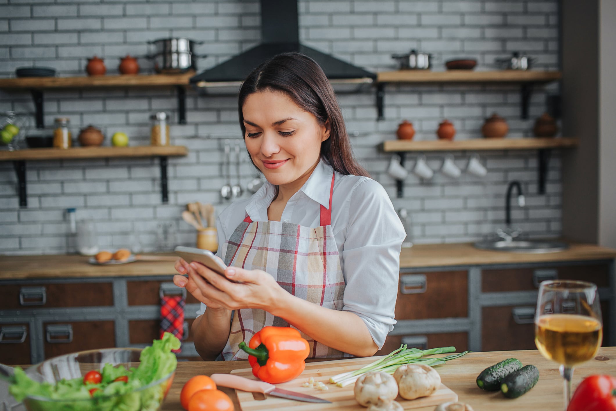 A woman cooking in her kitchen following a recipe on her phone