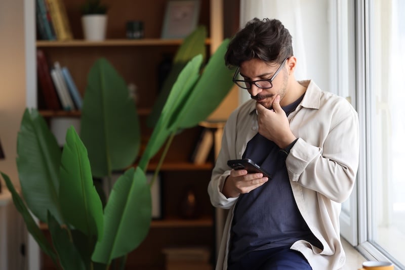 A man pondering his iPhone.